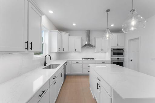 This stylish kitchen showcases a large center island, Shaker-style cabinetry, and brand-new stainless-steel appliances.