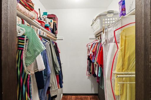 Primary Walk-in Closet with abundant hanging space and upper shelving
