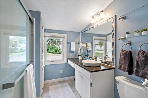 A cheerful full bath with a mosaic-framed mirror, vessel sink, and plenty of natural light
