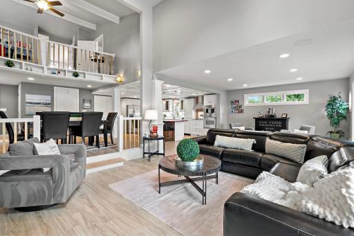 A true great room — soaring ceilings, a loft overlook, and an easy flow from kitchen to dining to living make this the heart of the home