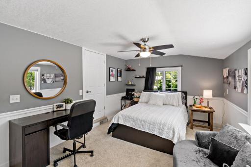 A generously sized bedroom with wainscoting detail, built-in desk space, and room to lounge — a great fit for a teen or guest suite