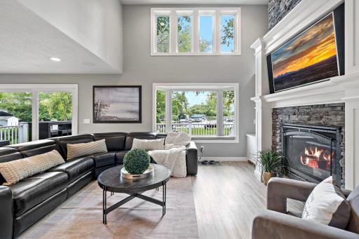 Two-story windows and a floor-to-ceiling stone fireplace anchor a living room built for cozy nights in and lake views by day