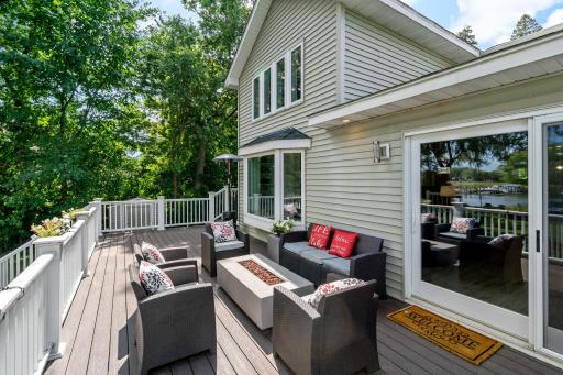Deck built for lake living — cozy fire table seating, room to spread out, and water views right off the sliding doors.