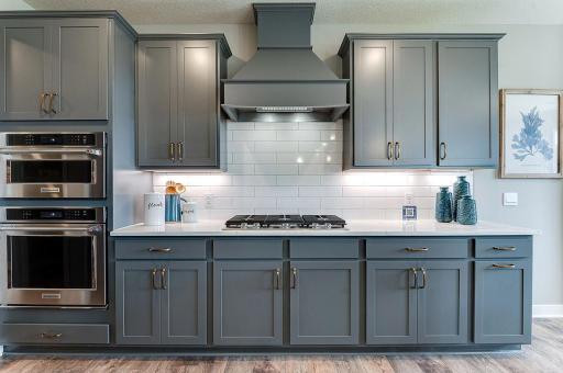 The family chef will be impressed with this gourmet kitchen! A 5-burner gas cooktop, built-in wall oven and microwave, quartz counters, tile backsplash, and a vent hood that vents to outside. Photos of model home, colors and finishes may vary.