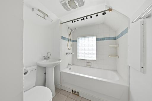 Bathroom with pedestal sink, bathtub with ceramic tile surround, handheld showerhead, new light fixture, and ceramic tile flooring also!