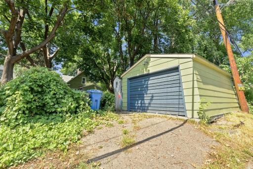 Freshly painted matching garage behind home with 220 electrical, a workbench, and a new remote door opener!