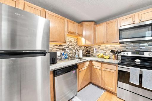 Kitchen workspace equipped with stainless steel range, matching range hood, and ample prep counters.