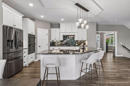 This spacious kitchen has an elevated feel with a walk-in pantry, wall oven, upgraded appliances, and an abundance of storage.