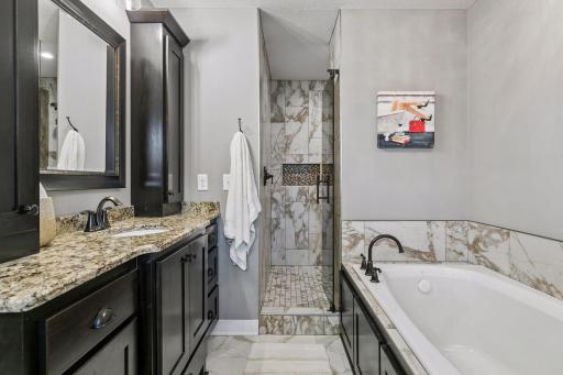 The primary bath features a beautifully tiled walk-in shower plus a separate soaking tub for the best of both worlds.
