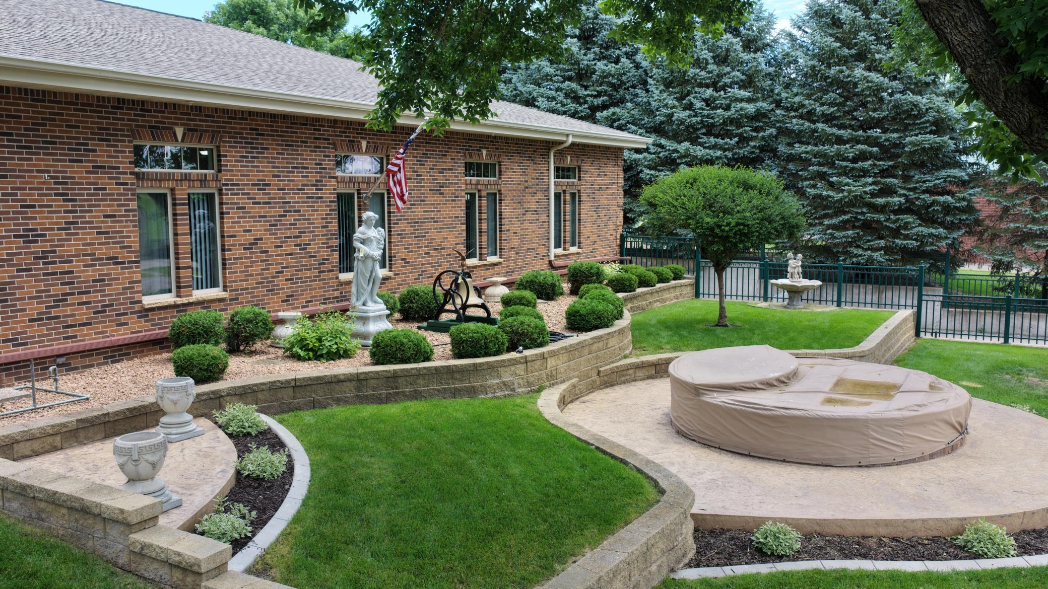 Landscaped side courtyard featuring a decorative fountain and access to the lower-level climate-controlled garage/flex space.