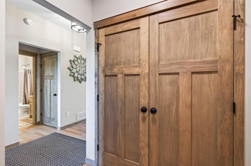 A view in the mudroom looking towards the main floor full bathroom. Note large real wood swing doors on mudroom closet.