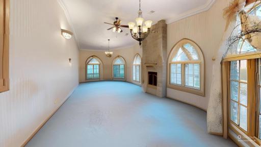 Same dramatic space with furnishings digitally removed to showcase the arched windows, fireplace, natural light, and architectural character