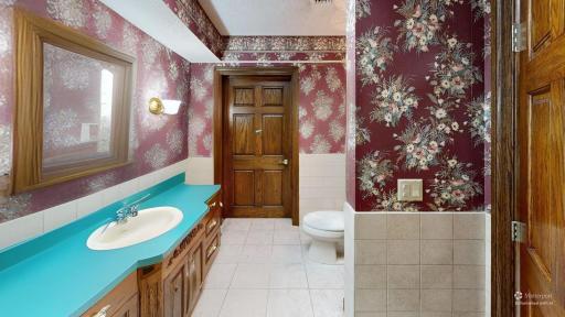 Lower-level full bathroom with generous vanity space, tiled finishes, and distinctive character details.