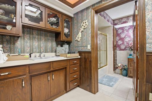 Lower-level built-in serving area with custom cabinetry, adjacent full bath, and generous storage