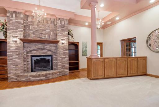 Expansive main-level gathering space with oak hardwood floors, columns, and fireplace feature