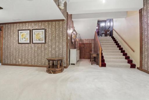 Additional finished lower-level flex space with open layout and adjoining rooms. Staircase to main entrance.