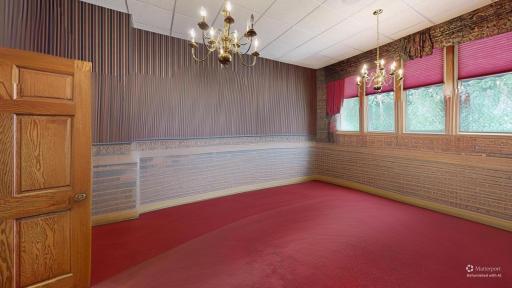 Elegant flex space shown with furnishings digitally removed highlighting custom woodwork, expansive windows, and chandelier lighting.