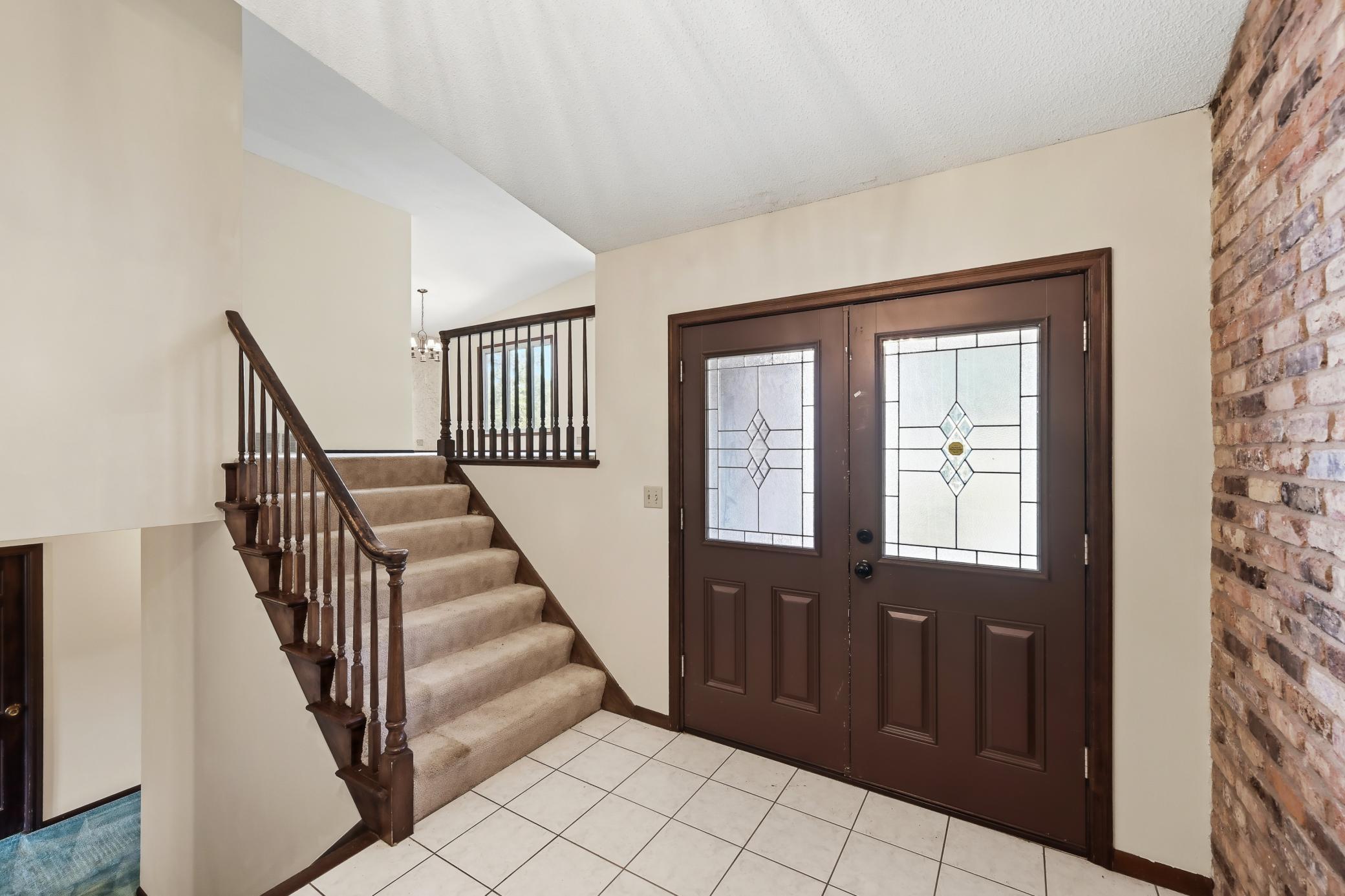 Welcoming foyer with tile floors! One wall with real brick! Original double front doors!