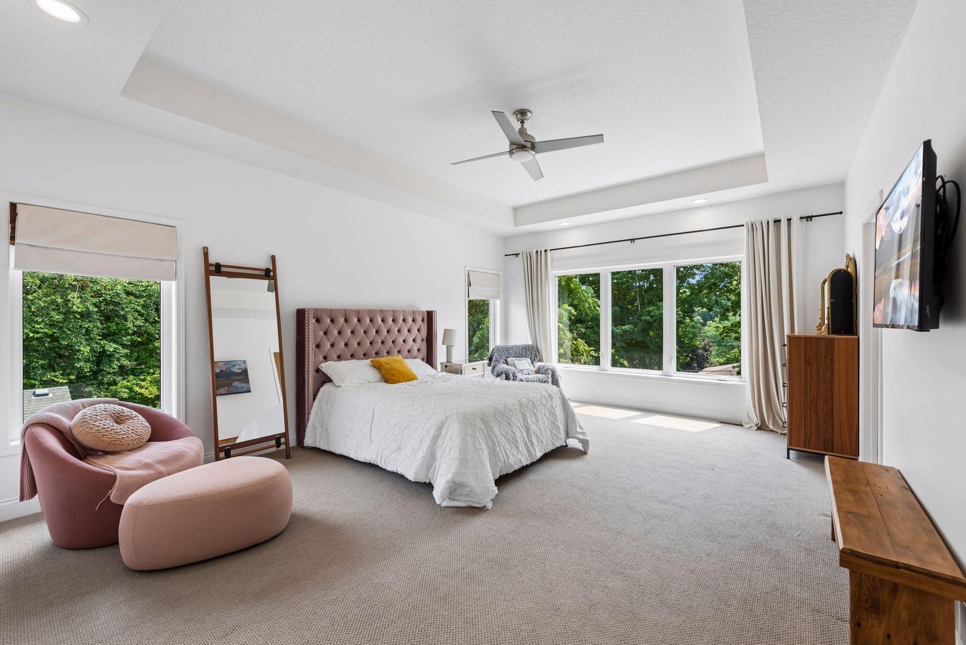 Escape to the spacious primary suite featuring oversized windows, soaring ceilings, and plenty of room for a sitting area. Natural light pours in, creating a peaceful retreat.