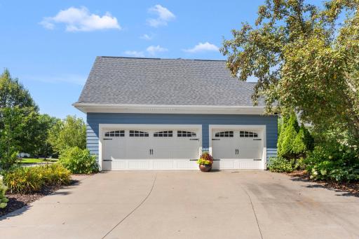 The home includes a concrete driveway and a 3-car attached side-load garage. The heated garage features epoxy floors and a high 10-ft ceiling. The roof was replaced in 2023 with architectural shingles and includes gutters and downspouts.