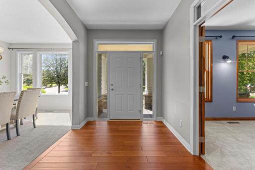 Spacious, light-filled foyer showcasing gorgeous cherry hardwood floors, flanked by the formal dining room and a dedicated home office/den.