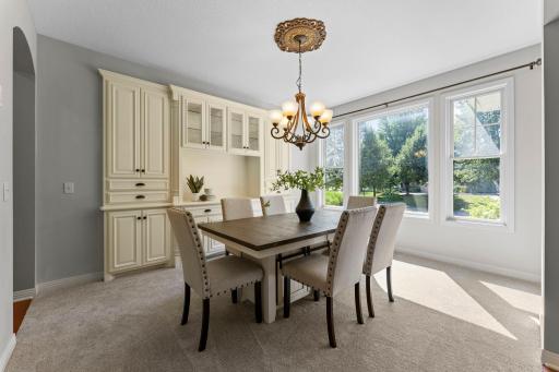 The formal dining room features a wall of windows filling the room with natural light. All your serving dishes and linens can be conveniently stored in the white acrylic enameled built-in cabinets and buffet.