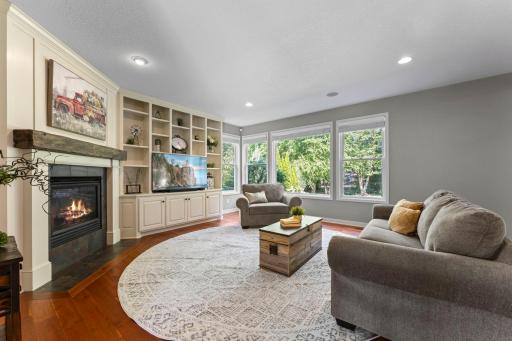 The remodeled living room includes a wall of built-in white acrylic enameled cabinetry and shelves.