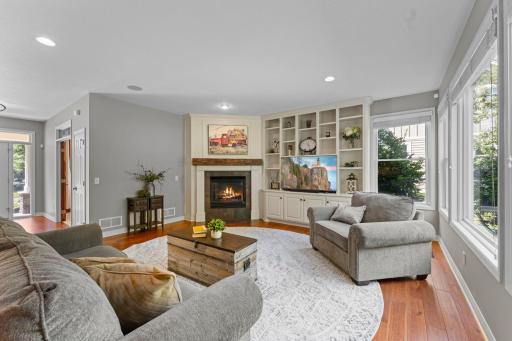 The living room features cherry hardwood floors, recessed lights, surround sound speakers, built-in cabinets and large windows filling the room with natural light.