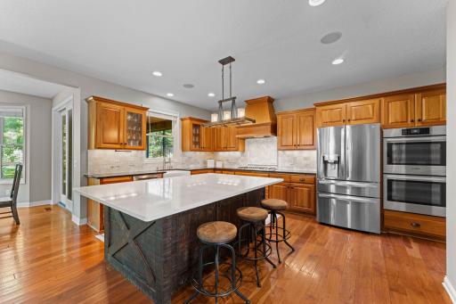 The kitchen features a large custom Amish-made island with a Cambria top, storage cabinets, and a microwave. The overhang on two sides provides space for 5-6 stools. The perfect place for entertaining.