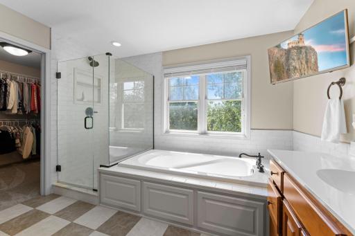 The spa-like private primary bathroom features a soaking tub, a glass walk-in shower, a separate water closet, and an impressive walk-in closet.