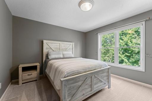 The second bedroom on the upper level features a large window overlooking the private backyard.