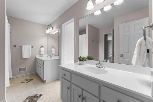 The full Jack and Jill bathroom features two separate vanities with storage, ceramic tile floors and a separate water closet with a window.