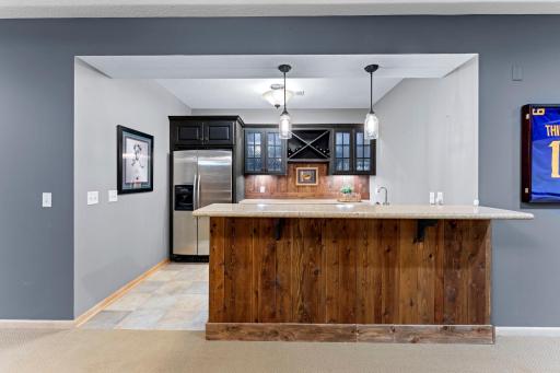 Get ready to entertain with the built-in bar featuring ceramic tile floors, a beautiful bar with room for 3-4 stools, a full-size refrigerator, storage, and a decorative wood backsplash.