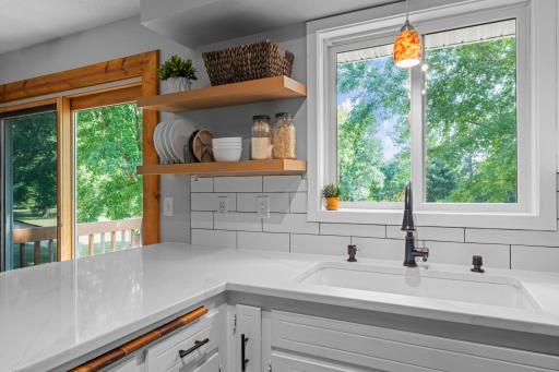 Tiled backsplash and a couple open shelves. Large sink and a great view to the backyard.