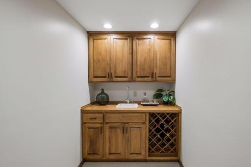 Stylish wet bar featuring a wine rack and custom built-ins adjacent to the lower-level family room.