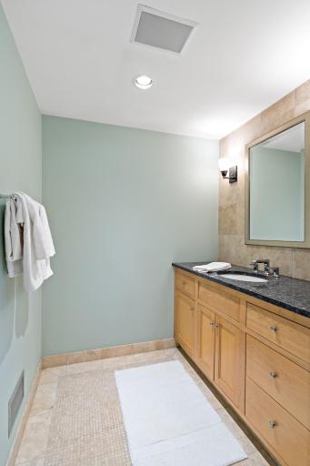 En suite bath with granite vanity, tiled shower, and direct access from the primary bedroom.