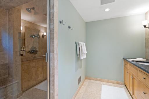A spa-like ensuite with a custom-tiled steam shower, granite vanity, tile floors, and serene sage tones - your own private retreat.