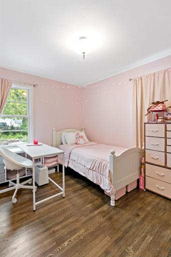 A sweet and sunny main floor bedroom with two windows, crown molding, and a peek of the backyard deck.