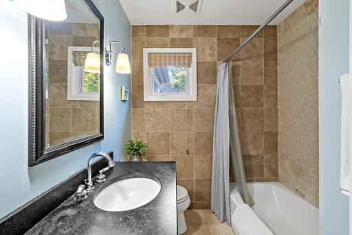 A well-appointed main-floor bath with a stone tile surround with a luxe soapstone vanity.