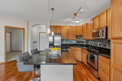 A beautifully appointed kitchen combines rich cabinetry, granite countertops, stainless steel appliances and a stylish glass-and-stone mosaic backsplash