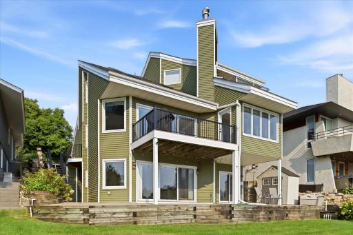 Prior Lake lakefront living! Lakeside exterior showcasing the newly installed deck railing system, multiple outdoor living spaces and direct access to the shoreline and private dock.