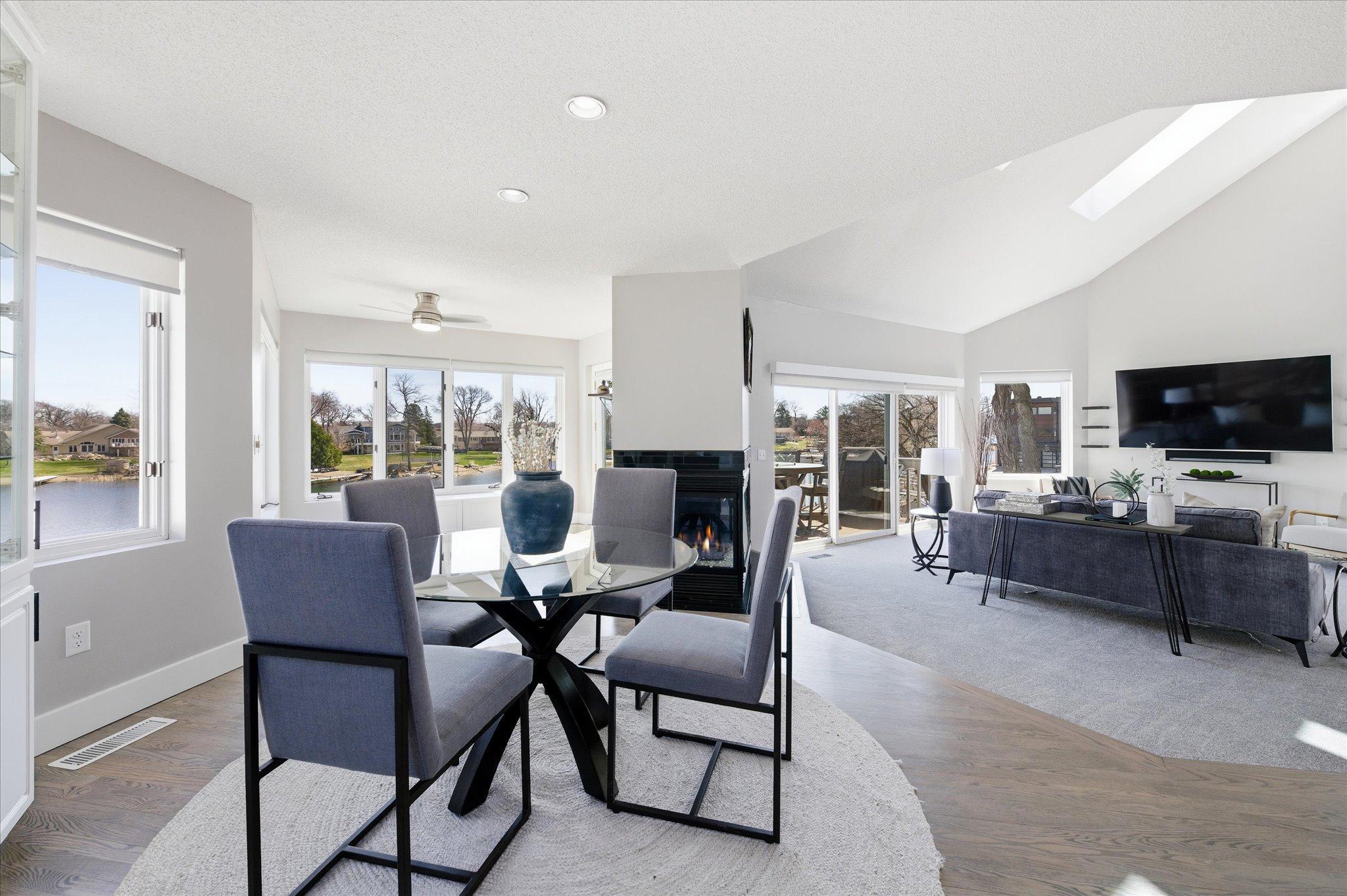 Open-concept main level featuring the dining area, living room with fireplace, vaulted ceiling, and lake views.