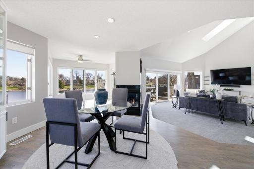 Open-concept main level featuring the dining area, living room with fireplace, vaulted ceiling, and lake views.
