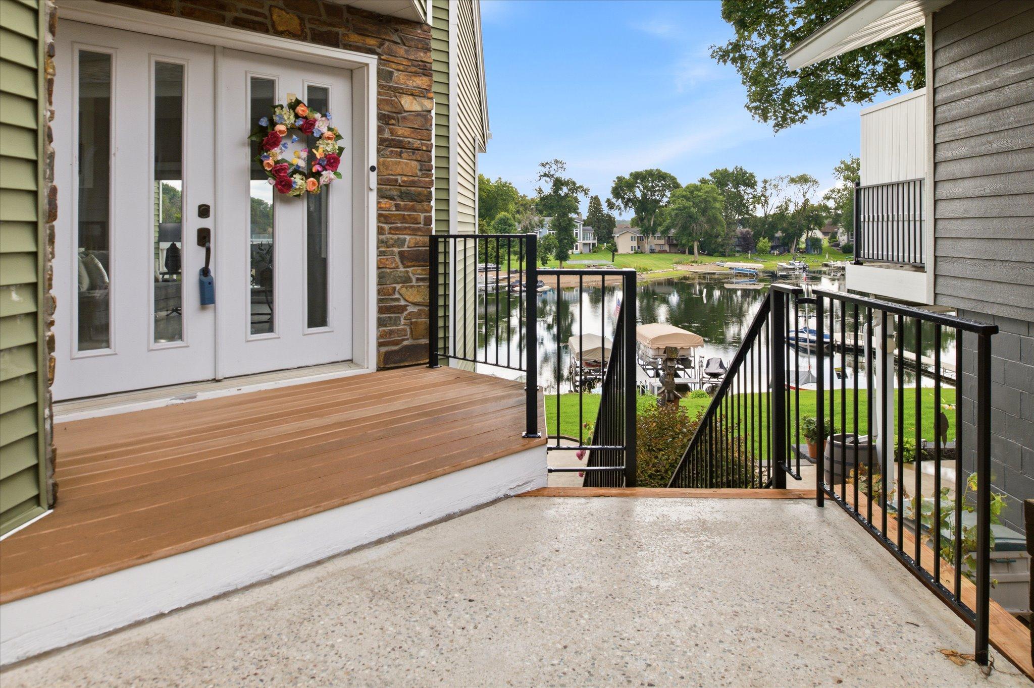 Updated front entry featuring newly installed black iron railings, composite decking, and natural stone accents.