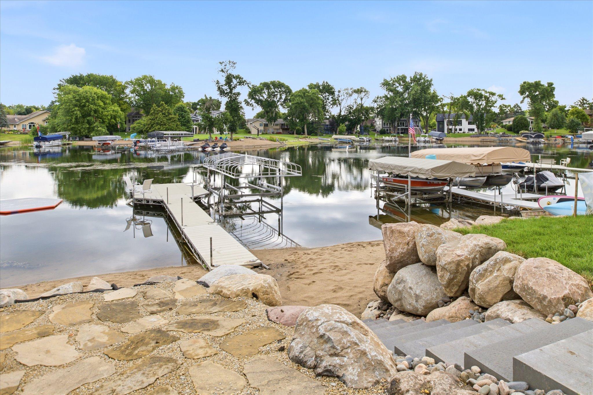 Private dock, sandy beach, and newly installed boulder shoreline retaining wall with panoramic views across the lake.