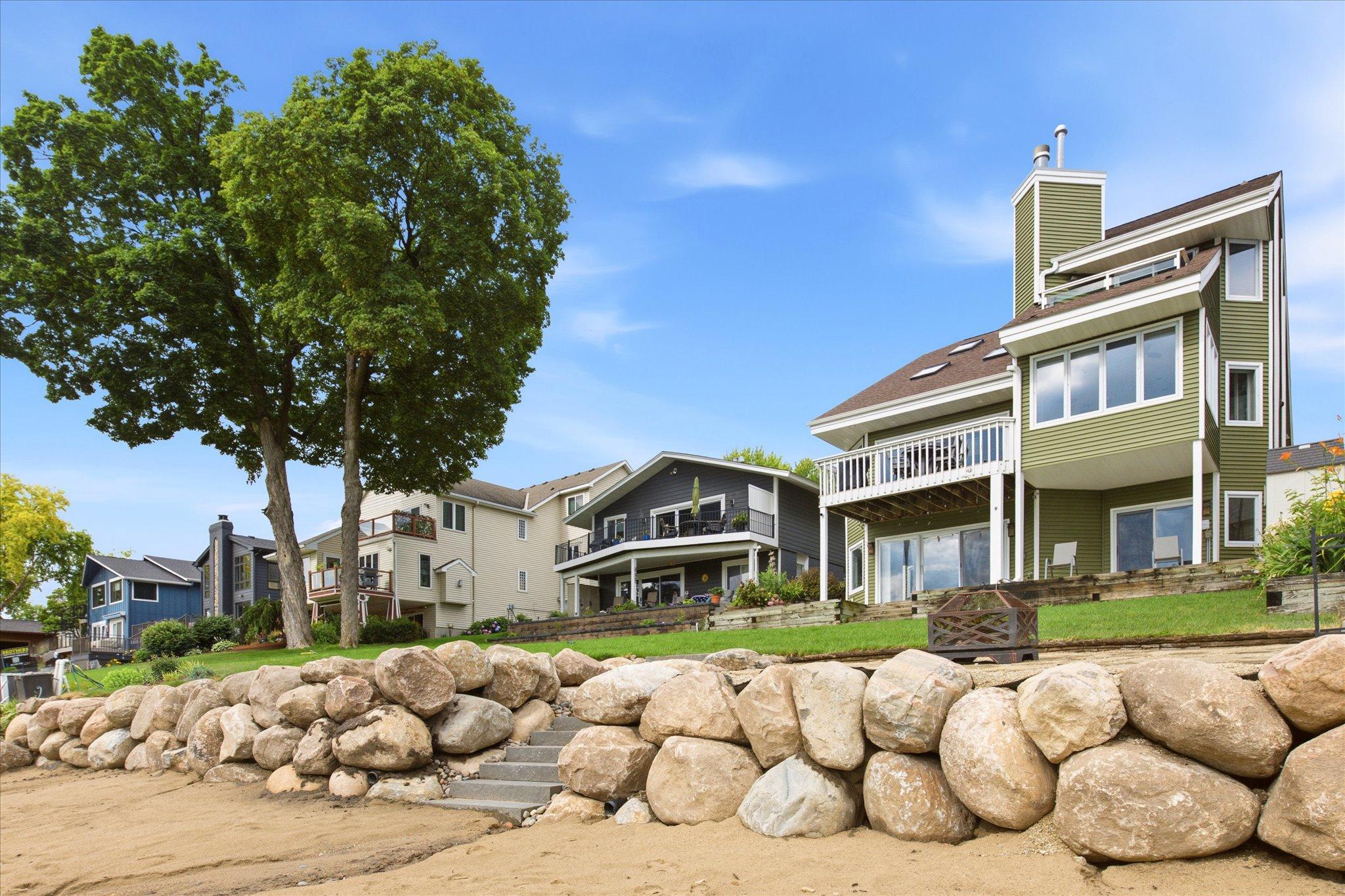 Rear elevation highlighting the recently installed boulder shoreline retaining wall and sandy beach.