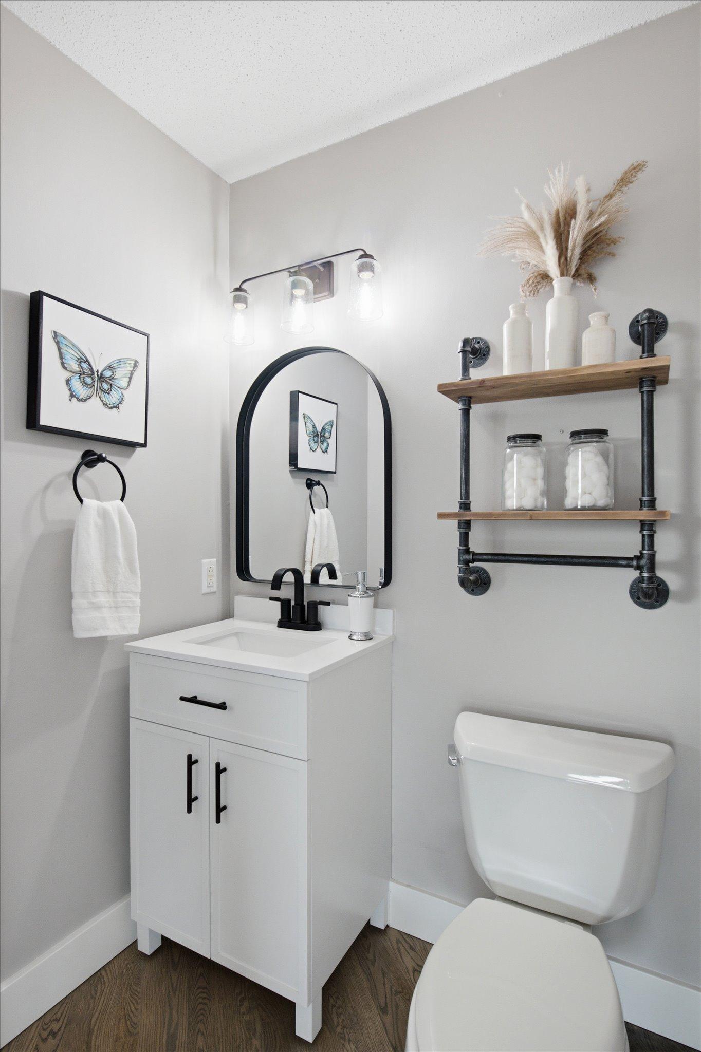 Updated main-level half bath with modern vanity, fixtures, and open shelving.