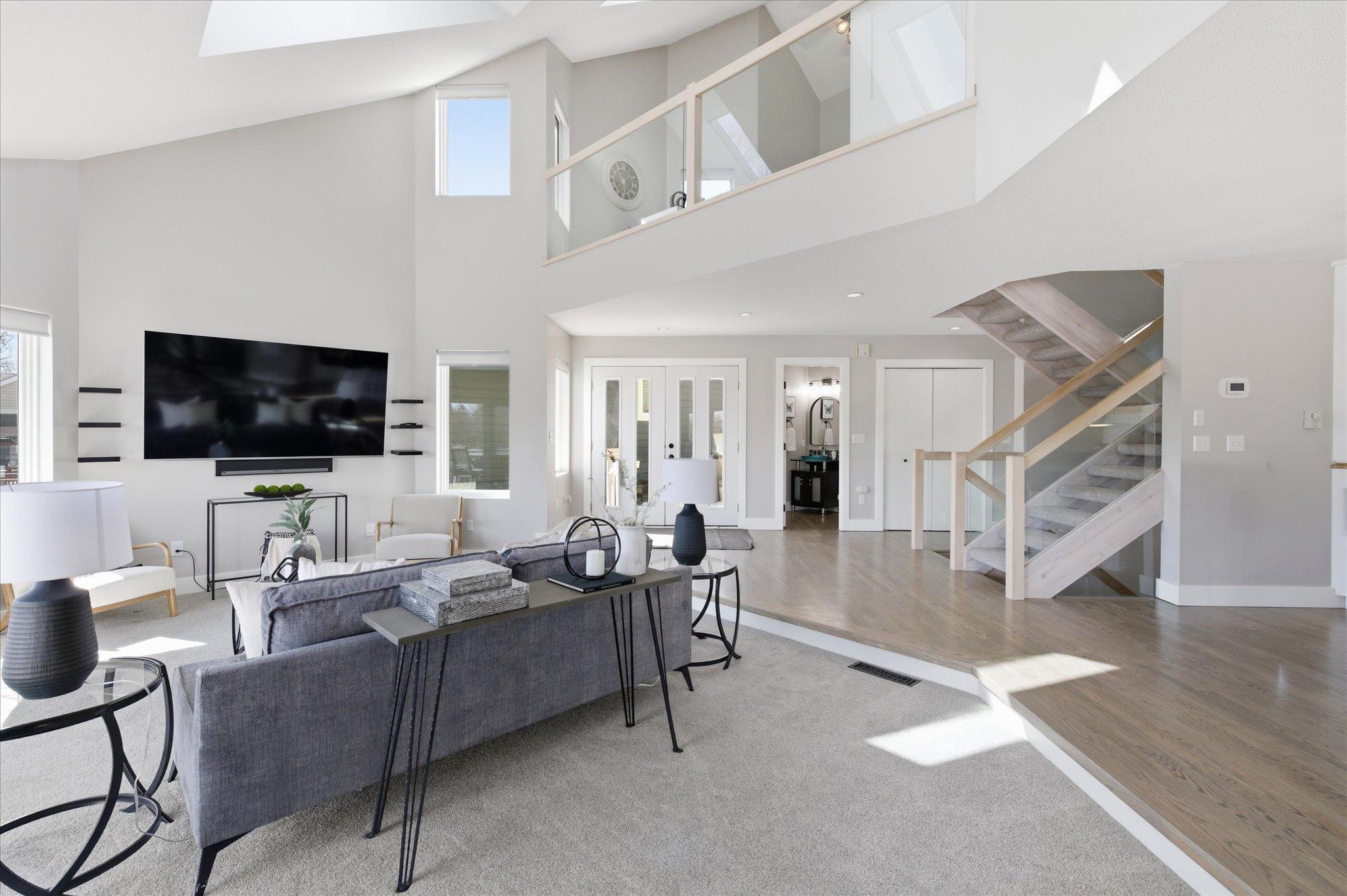 Great room with vaulted ceilings, skylights, open staircase, and abundant natural light.