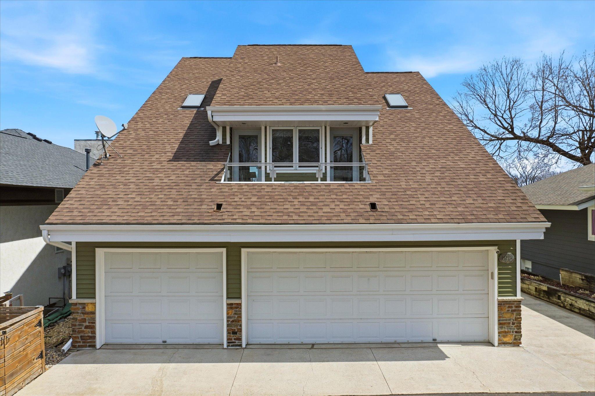 Front elevation highlighting the attached three-car garage and upper-level balcony.