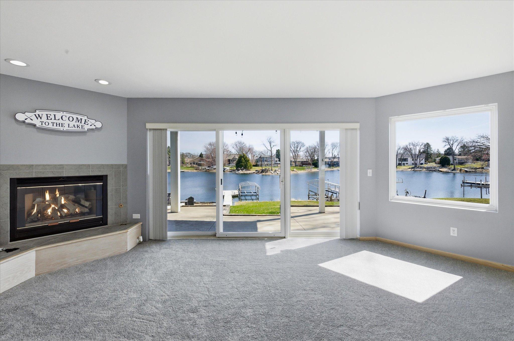 Walkout family room with gas fireplace, patio access, and expansive lake views.